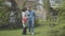 Adult woman walking with the basket with tulips in it on the backyard. Adult grandson comes and hugs the lady, the guy