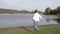 Adult woman walking towards a pond, admiring the wooded landscape