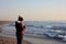 Adult woman walks by the sea, on the shoreline, checking her cell phone