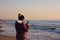 Adult woman walks by the sea, on the shoreline, checking her cell phone