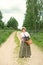 Adult woman walks through the woods park with a wicker basket with a bouquet of lupine flowers