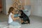 An adult woman in warm knitted socks and pajamas plays Christmas eve with her pet in a room on the floor