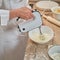 Adult woman in white chef clothes beats eggs with mixer for making pie in home kitchen