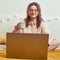 Adult woman works online on a home bed. The girl is sitting in the bedroom with a laptop amd coffe cup