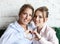 Adult woman and young woman stacking hands in heart sign looking at camera.