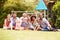 Adults and kids sitting on grass in a garden, group portrait