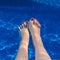 Adults woman`s feet with red nails underwater