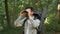 Advanced man backpacker looking through binoculars, planning route in forest, getting lost in woodland, free space