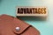 Advantages on a wooden block and brown leather wallet. Business concept