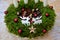 Advent candlestick made of moss and cones. shiny red balls and white four candles. table decoration with two white reindeer made o