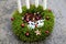 Advent candlestick made of moss and cones. shiny red balls and white four candles. table decoration with two white reindeer made o