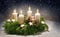 Advent wreath from evergreen branches with white candles, the fourth is burning for the time before Christmas, dark snowy