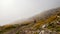 A adventure biker on motorbike going over mountain in bad weather and fog