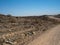 Adventure journey scene on dirt road trip through Namib desert hot dried landscape to rock mountain horizon with local plant