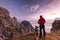 Adventure Man with Dog at High Mountains Peak at Sunrise. Togetherness and Friendship Concept