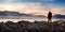 Adventure Man standing on rocky shore by the lake with mountains in background. 3d Rendering.