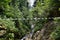 Adventure via ferrata hiking trail with a rope bridge over a gorge with stream and green plants