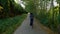 Adventure Woman bike riding on a bicycle trail surrounded by green trees.