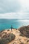 Adventurer with a backpack stands on the edge of a cliff and observes the beautiful group of yellow-gold rocks of Punta de la