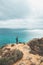 Adventurer with a backpack stands on the edge of a cliff and observes the beautiful group of yellow-gold rocks of Punta de la