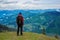 Adventurer with backpack stands on the green mountain meadow