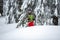 Adventurer with firewood in his hands is walking in snowshoes