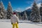 Adventurer stands among huge fir trees covered with snow