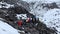 Adventurous climbers with backpacks and trekking poles walk over the rocks to the top of the volcano.