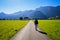 Adventurous hiker walking on the road leading to the beautiful mountains covered in greens