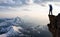 Adventurous Man Hiker With Hands Up on top of a Steep Rocky Cliff