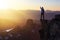 Adventurous Man Hiker With Hands Up on top of a Steep Rocky Cliff.