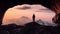 Adventurous Man Hiker standing in a cave with dramatic cloud and snowy mountain view