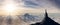 Adventurous Man Hiker standing on top of icy peak with rocky mountains in background.