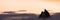 Adventurous Man Hiker Standing on top of a rocky mountain overlooking the dramatic landscape at sunset.