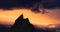 Adventurous Man Hiker Standing on top of a rocky mountain overlooking the dramatic landscape at sunset.