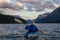 Adventurous Man Kayaking in Glacier Lake surrounded by the beautiful Canadian Rocky Mountains