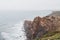 Adventurous man standing on the edge of a cliff enjoys the view of the Atlantic coast in the Odemira region of southwestern