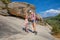 Adventurous mother and daughter with trekking sticks posing in rocky mountain