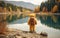 An adventurous teddy bear looking at a pretty landscape with a lake.