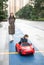 Adventurous Toddler Drives Red Sports Car with Joyful Glee Accompanied by his mother