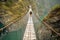 Adventurous Traveler Crossing Rope Bridge Over Deep Valley - AI Generative