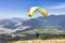 Adventurous Woman Flying on a paraglider around the Canadian Mountain Landscape