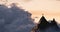 Adventurous Woman Hiker Standing on top of a rocky mountain overlooking the dramatic landscape at sunset