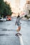 Adventurous woman riding on a skateboard on an empty city road early in morning