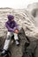 Adventurous woman is sitting next to the great Dettifoss waterfall in Iceland watching the water