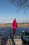 Adventurous young woman on a pier with a wooden boat. Freedom. Reflection