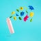 Advertisement idea with pink deodorant, colorful summer flowers and green leaves against pastel blue background. Minimal nature