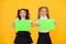 Advertising idea for school. Happy girls holding paper sheets for certain idea on yellow background. Small cute kids