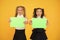 Advertising idea for school. Happy girls holding paper sheets for certain idea on yellow background. Small cute kids