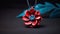 Advertising shot of a pendant shape of red flower, made of polymer clay, isolated on dark black background